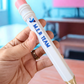 Hand holding a pen with 'YMER TEAM' branding in an indoor setting